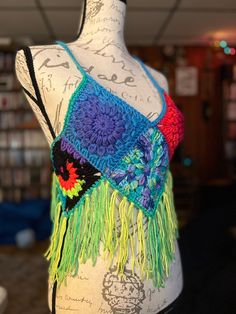 a mannequin wearing a colorful crocheted top with fringes on it