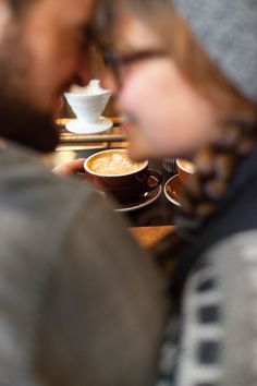 two people sitting at a table with cups of coffee