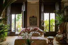 a living room filled with lots of furniture and plants on the windows sills