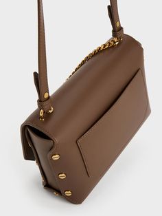 Subtle, tasteful details can instantly change up a look, and this Clea chain-handle bag is a case in point. The classic front-flap silhouette appears clean and minimal at first glance, making the screw accents on the sides stand out against the muted dark brown finish. To complement the edgy design, metallic chain-links add boldness to the classic feminine style. Complete with an accompanying adjustable strap, this chic carrier makes a quiet statement. Classic Feminine Style, Clean And Minimal, Classic Feminine, Edgy Design, Side Stand, Chain Links, Charles Keith, Handle Bag, Feminine Style