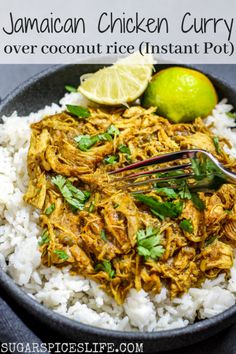 a bowl filled with rice and chicken curry next to a lime wedge on the side