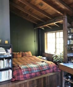 a bed sitting under a window next to a book shelf filled with lots of books