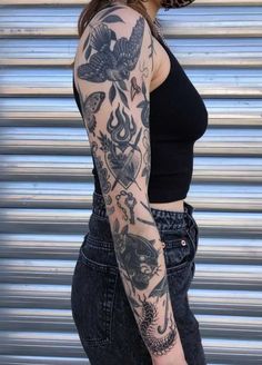 a woman with a tattoo on her arm and leg is standing in front of a garage door