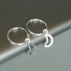 A PAIR of sterling silver hoops. Comes with a detachable cut out crescent moon charm. The charm is multipurpose and can be used with a neck or bracelet chain too. Dimension: Hoop- 15 x 1.5 mm Charm: 6 x 12 mm Drop length- 23 mm These earrings are made of 925 hypoallergenic sterling silver and plastic. Please note this price is for ONE PAIR. All my pieces are sent in a gift box. I can include a personal message from you if needed You are welcome to contact me at... bhavnakwintra1956@gmail.com For Adjustable Silver Celestial Hoop Earrings, Celestial Silver Hoop Earrings Hypoallergenic, Nickel-free Celestial Silver Hoop Earrings, Silver Crescent Cartilage Earrings With Moon Charm, Celestial Nickel-free Silver Hoop Earrings, Silver Celestial Huggie Earrings, Celestial Small Hoop Sterling Silver Jewelry, Sterling Silver Cartilage Earrings With Moon Charm For Gift, Celestial Sterling Silver Small Hoop Jewelry