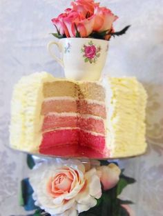 three layered cake with flowers and a cup on top