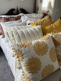 a bed topped with lots of white pillows and yellow throw pillows on top of it