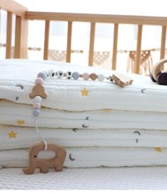 a stack of white blankets sitting on top of a bed next to a toy elephant