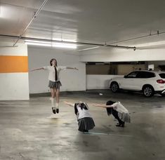 two girls are doing tricks in an empty parking garage while another girl is on the ground