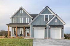 a large gray house with two garages on the front and one car door open