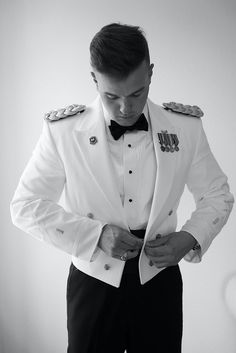 a man in a tuxedo adjusts his bow tie as he looks down