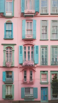 a pink building with blue shutters and windows