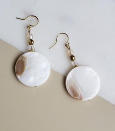 Solazur earrings "Shella" --- Beautiful. Different. Feminine elegance. These earrings will add a pop of style and a boho breeze to your outfit. Seashells are the best summer and beach reminder, and wearing them will make you feel you're on vacation every day :-)  A blend of shell and glass, with an intricate glass shine while the shell's texture reflects its pearly glow from different angles.  The shell coins have a different pattern on each side. They will match beautiful with either a dress or Elegant Drop Earrings For Vacation, Elegant Pearl White Shell For Beach, Handmade Adjustable Pearl White Earrings, Bohemian Round Earrings For The Beach, Elegant Summer Jewelry With Shell Design, Elegant Shell Jewelry For Summer, Handmade Cream Earrings For Beach, Elegant Summer Shell Jewelry, Handmade Pearl Shell-shaped Earrings