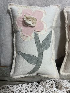 two pillows with flowers on them sitting next to each other, one has a flower in the middle