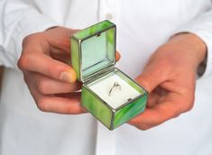 a person holding a ring box with a diamond in it