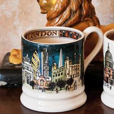 two coffee mugs sitting on top of a wooden table next to a bear statue