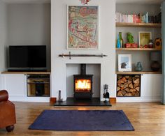 a living room with a wood burning stove in it's center and bookshelves on the wall