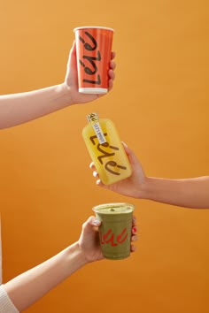 two people holding up cups with the words i love you written on them and one is holding a can