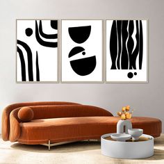 two black and white paintings hanging on a wall next to a couch in a living room