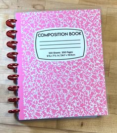 a pink composition book sitting on top of a wooden table