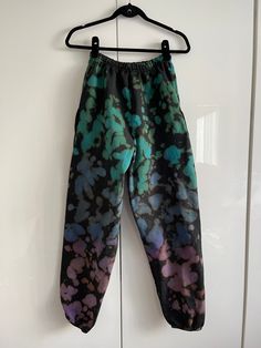 a pair of pants hanging on a hook in front of a white door with black and blue paint splatters