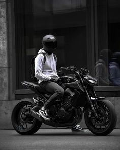 a person sitting on a motorcycle in front of a building