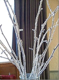 a vase filled with white branches in front of a window