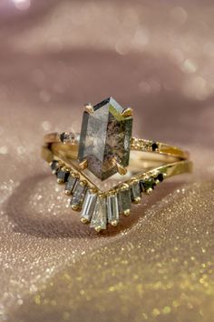 a diamond ring sitting on top of a gold cloth covered table with sparkles in the background