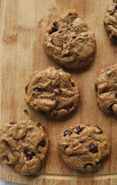 eight chocolate chip cookies on a wooden cutting board