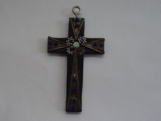 a cross with blue and white beads hanging from it's side on a wall