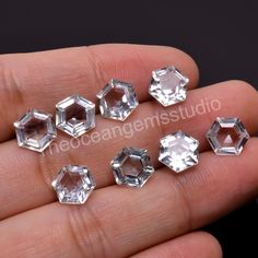 five clear hexagonal diamonds sitting on someone's hand