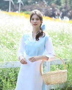 a woman in a blue and white dress holding a basket