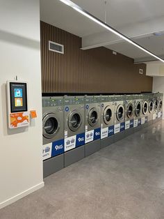 a row of washers in a public laundment with an appliance on the wall