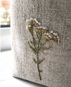 a close up of a flower embroidered onto a pillow cover on a window sill