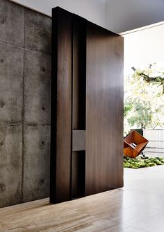 an open door leading into a room with concrete walls and floor to ceiling glass doors