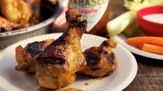 chicken legs on a plate with carrots and other food items in the back ground