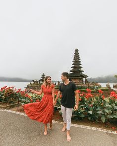 a man and woman are walking in front of flowers with an island in the background