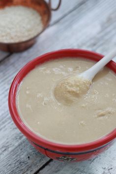 a red bowl filled with batter on top of a white wooden table next to two brown bowls