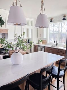 a kitchen with two lights hanging from the ceiling and a dining table in front of it