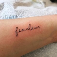 the word fearless written in cursive handwriting on someone's arm with a tattoo