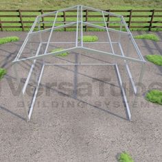 a metal structure sitting on top of a dirt field