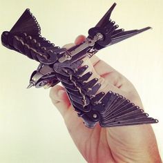 a hand holding a small black bird made out of metal parts with spikes on it's wings