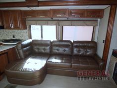 a brown leather couch sitting inside of a living room next to a stove top oven