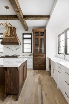 a large kitchen with wooden floors and white counter tops on both sides of the room