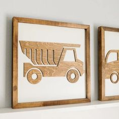 two wooden framed art pieces depicting trucks on the wall next to each other, one with a smaller truck in it