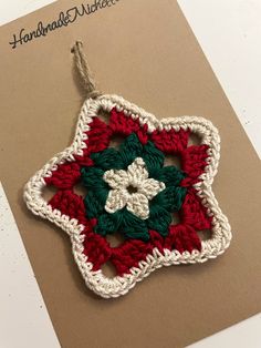 a crocheted ornament is hanging on a piece of carding paper