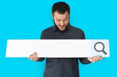 a man holding up a sign with a magnifying glass on top of it