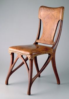 a wooden chair with leather upholstered on the back and seat, against a gray background