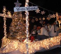 people are riding in a boat decorated with lights and snowflakes on the street