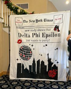 a woman taking a picture of a banner with the words delta phi epsion on it