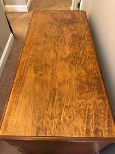 a wooden table sitting on top of a carpeted floor next to a door way